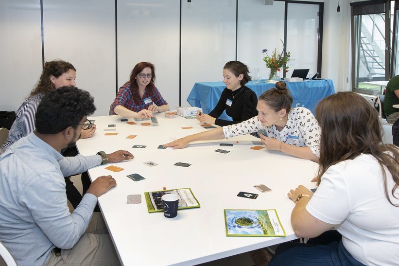 Spelers zitten aan een tafel Cards for Biosafety te spelen