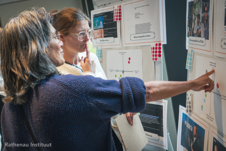 Twee mensen wijzen naar een poster