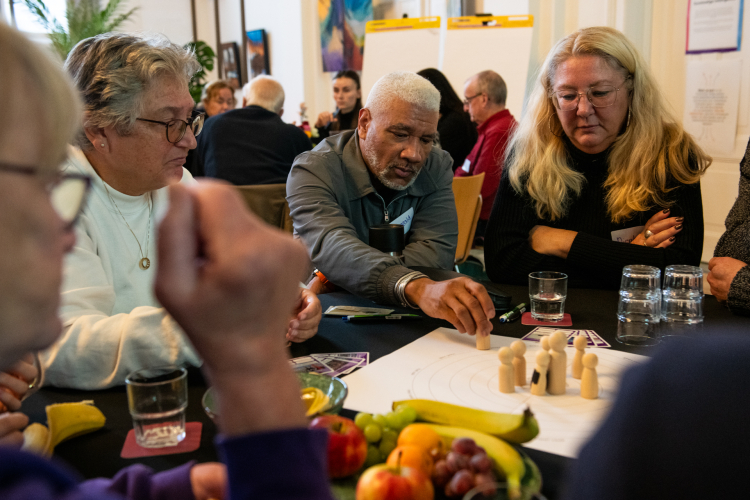 Deelemers aan een tafel zetten houten poppetjes op een papier