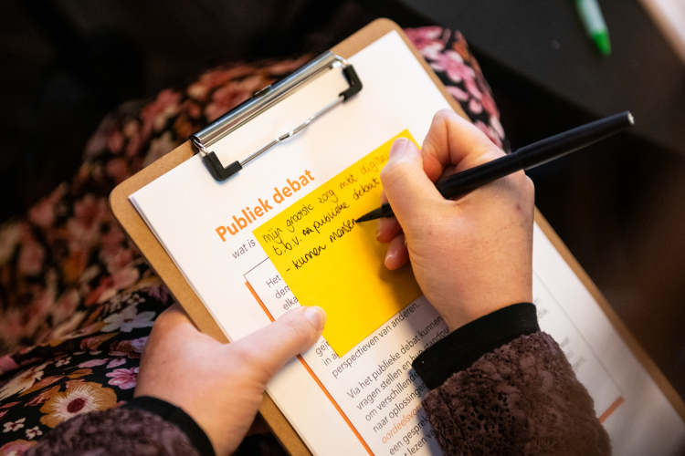 Iemand schrijft zijn grootste zorg op, op een papier met een klipbord