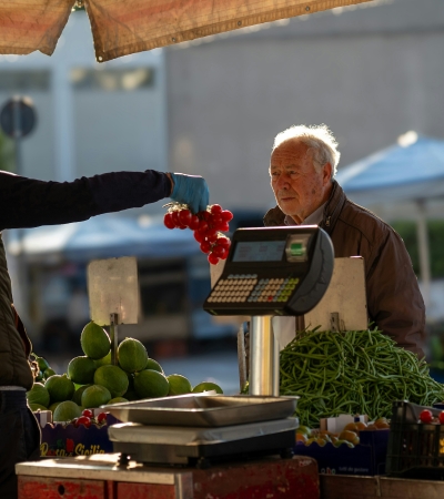 Marktkoopman overhandigt tomaten, koper twijfelt