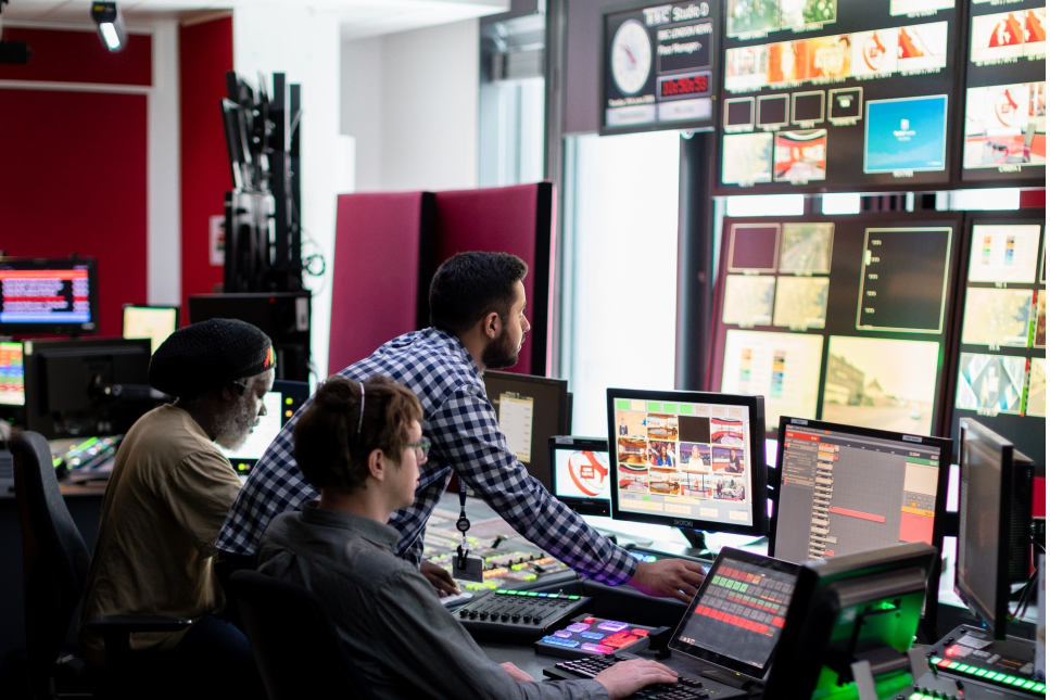 Medewerkers kijken in de control room mee op de verschillende schermen