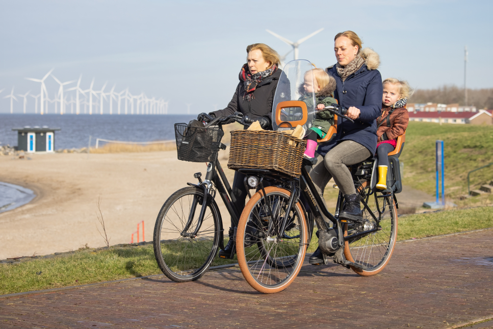 Fietsers langs het IJsselmeer met op de achtergrond windmolens