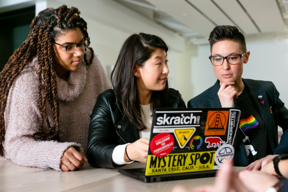 Drie mensen aan het werk op een laptop