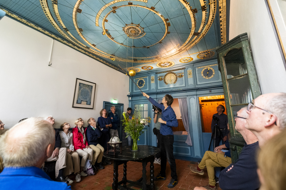 Bezoekers van het Eise Eisinga Planetarium krijgen uitleg over de werking ervan.