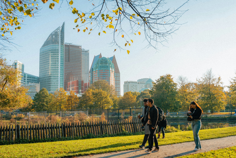 Mensen wandelen in park met op achtergrond skyline Den Haag