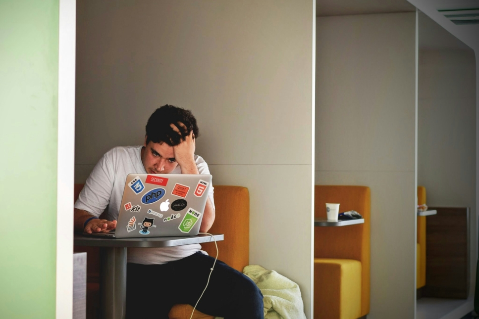 Man met laptop in hokje en hand in het haar