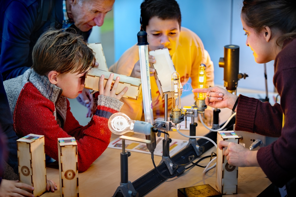 Kinderen kijken naar het lichtspectrum van verschillende lampen tijdens het Weekend van de Wetenschap. Foto: Digidaan