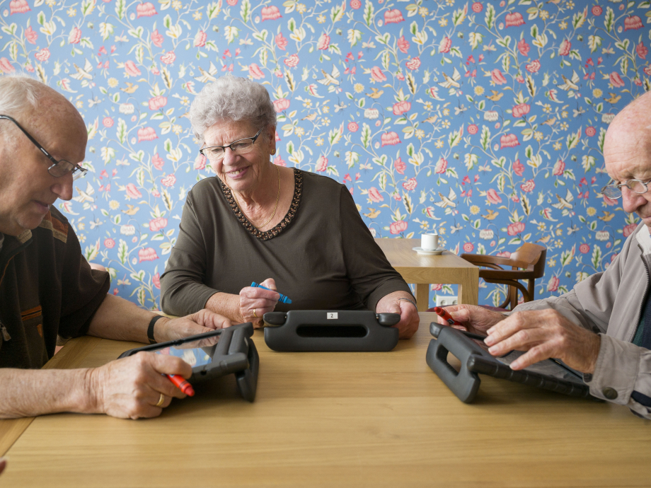 Drie oudere mensen zitten samen te werken op hun laptops