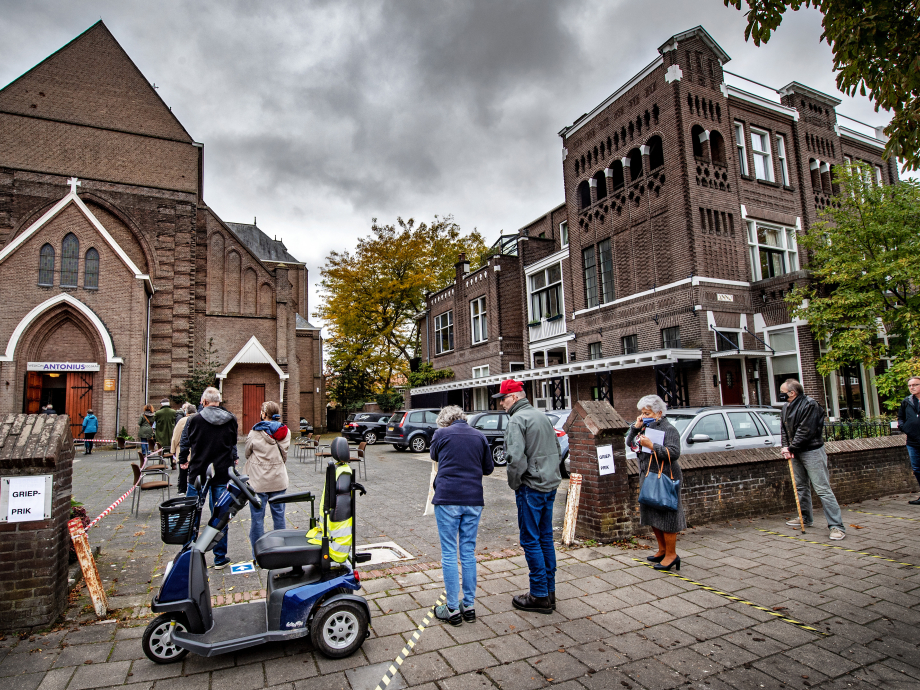 Ouderen in Nijmegen wachten voor het kerkgebouw waar ze dit jaar hun griepprik krijgen