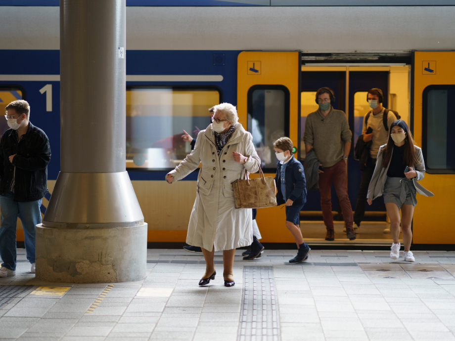 Mensen met mondkapjes op stappen uit de trein