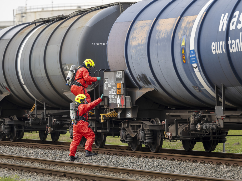 Mannen in beschermende pakken bij treinwagons 