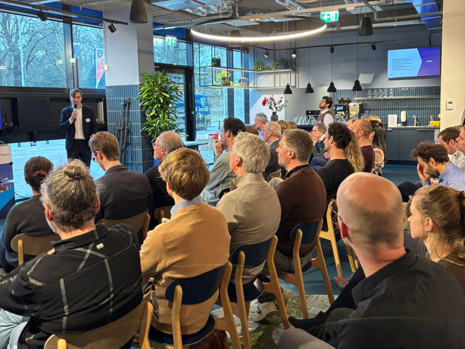 Twintig personen in een zaal kijken naar een scherm