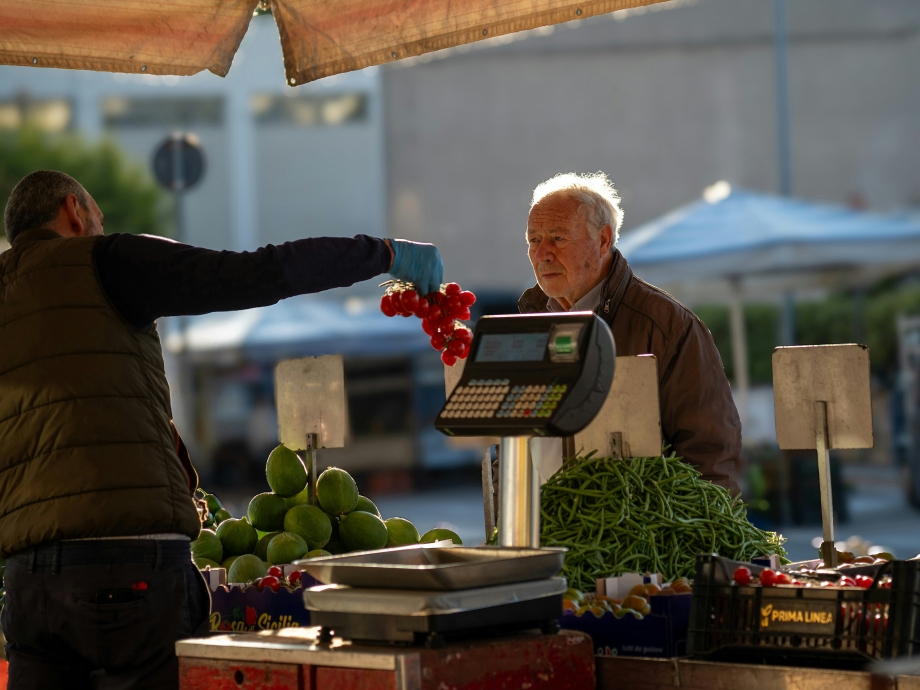 Marktkoopman overhandigt tomaten, koper twijfelt