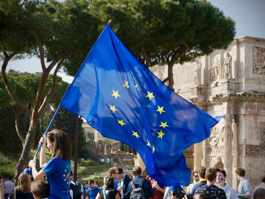 Een meisje houdt temidden van allerlei mensen een Europese vlag vast. 