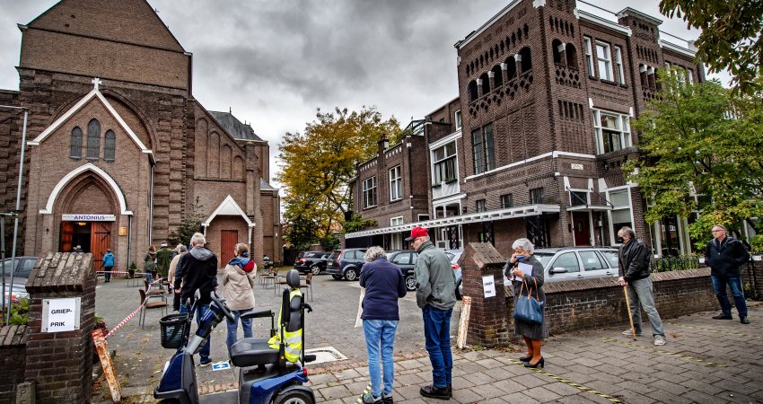 Ouderen in Nijmegen wachten voor het kerkgebouw waar ze dit jaar hun griepprik krijgen