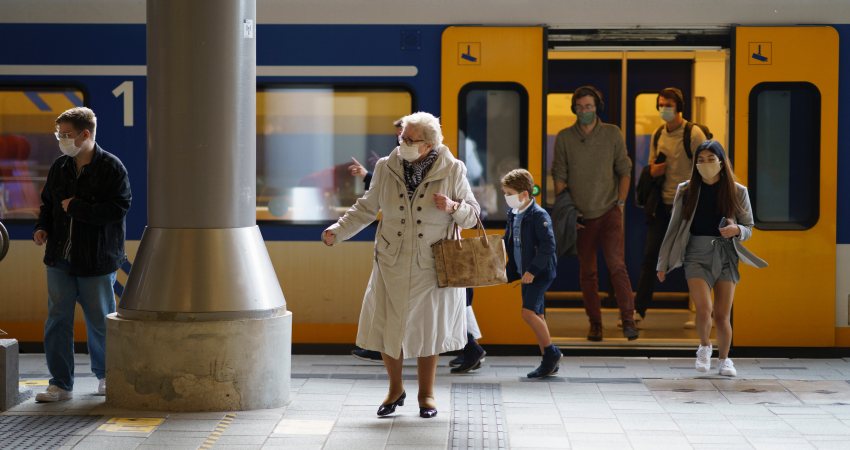 Mensen met mondkapjes op stappen uit de trein