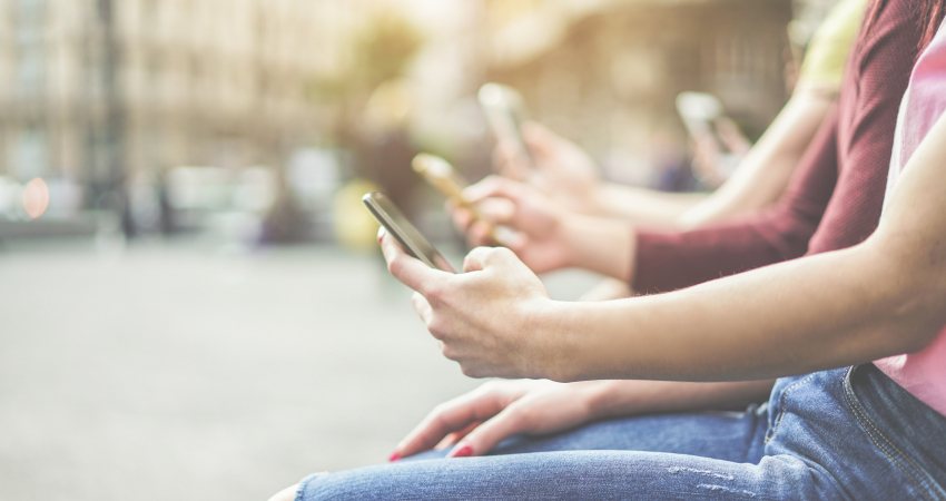 Twee mensen kijken op een bankje op straat op hun telefoon