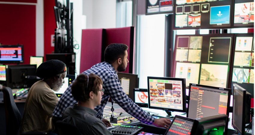 Medewerkers kijken in de control room mee op de verschillende schermen