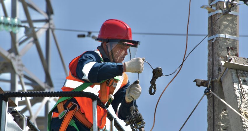 Een man aan het werk bij een electriciteitspaal