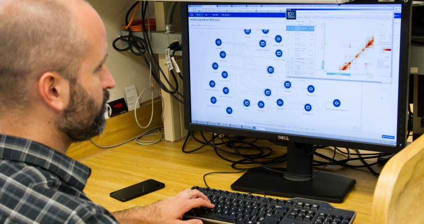 Een man analyseert grote hoeveelheden data op zijn computer voor kankeronderzoek