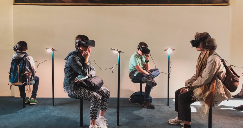 4 personen zitten met een VR bril op voor een kunstwerk
