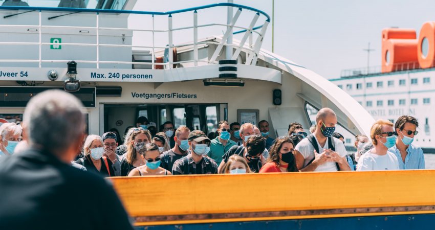 Het pondje over het IJ in Amsterdam vol met mensen met mondkapjes op