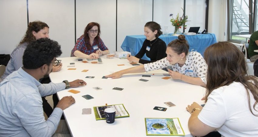Spelers zitten aan een tafel Cards for Biosafety te spelen