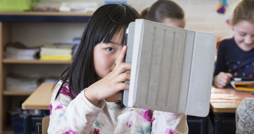 Een meisje houdt haar tablet vast in de klas op een tabletschool in Lopik