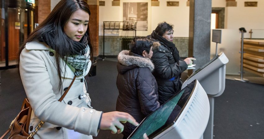 Een mevrouw trekt een nummer voor de balie van het Stadskantoor in Rotterdam