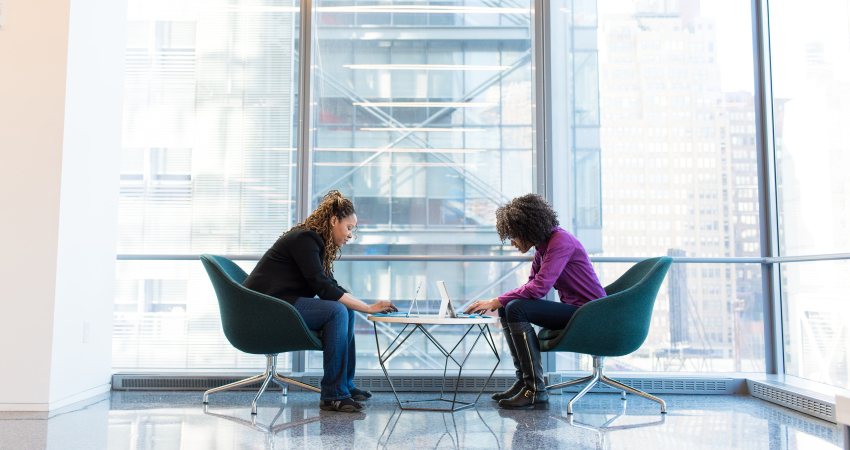 twee vrouwen werken tegenover elkaar op laptops