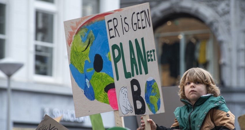 Een kind draagt een protestbord tijdens een klimaatmars in Amsterdam