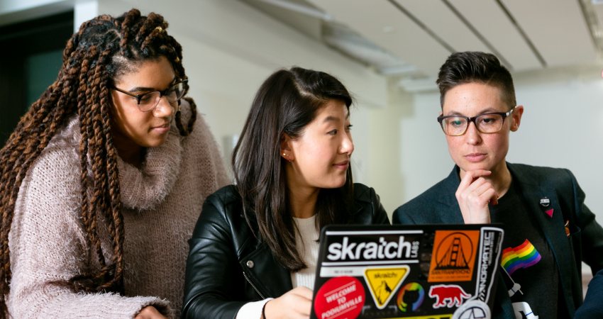 Drie mensen aan het werk op een laptop