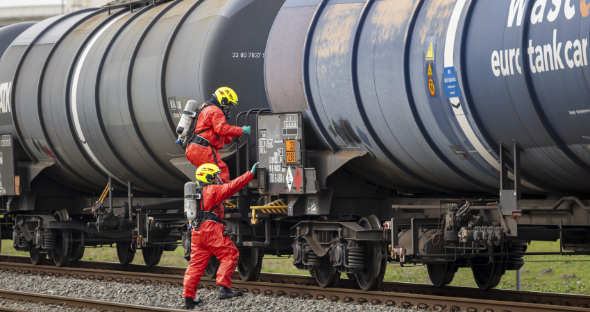 Mannen in beschermende pakken bij treinwagons