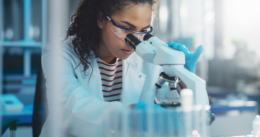 Vrouw kijkt door microscoop