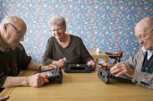 Drie oudere mensen zitten samen te werken op hun laptops