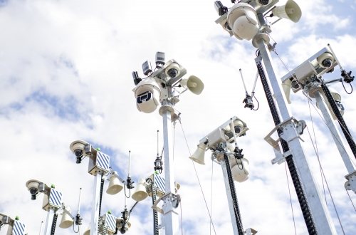 Een woud van surveillancecamera's tegen een bewolkte hemel