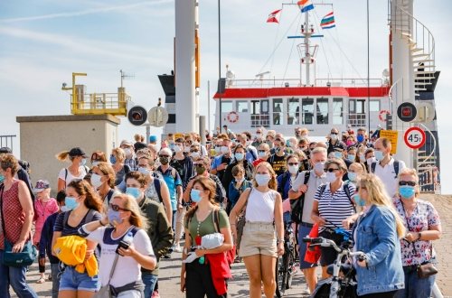 Tientallen mensen met mondkapje lopen van een veerboot af