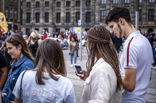 Mensen op straat in Amsterdam die op hun telefoon kijken. Coverfoto rapport initiatieven voor digitale democratie op nationaal niveau.