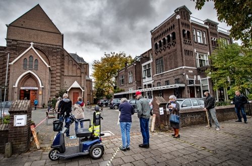 Ouderen in Nijmegen wachten voor het kerkgebouw waar ze dit jaar hun griepprik krijgen