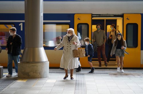 Mensen met mondkapjes op stappen uit de trein