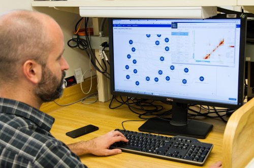 Een man analyseert grote hoeveelheden data op zijn computer voor kankeronderzoek
