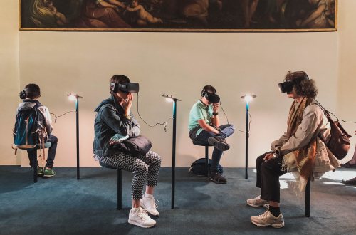 4 personen zitten met een VR bril op voor een kunstwerk