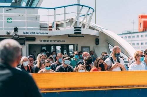 Het pondje over het IJ in Amsterdam vol met mensen met mondkapjes op