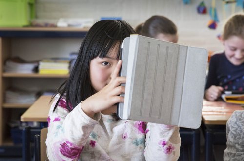 Een meisje houdt haar tablet vast in de klas op een tabletschool in Lopik