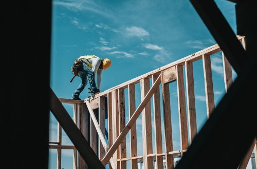 Een bouwvakker staat bovenop een houten frame
