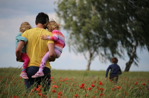 Een vader loopt met zijn kinderen door een bloemenveld