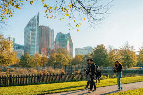 Mensen wandelen in park met op achtergrond skyline Den Haag