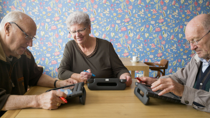 Drie oudere mensen zitten samen te werken op hun laptops