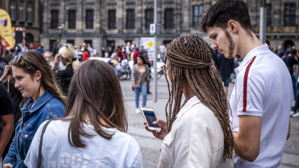 Mensen op straat in Amsterdam die op hun telefoon kijken. Coverfoto rapport initiatieven voor digitale democratie op nationaal niveau.